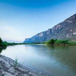 River with mountains and greenery in the background.