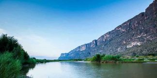 River with mountains and greenery in the background.
