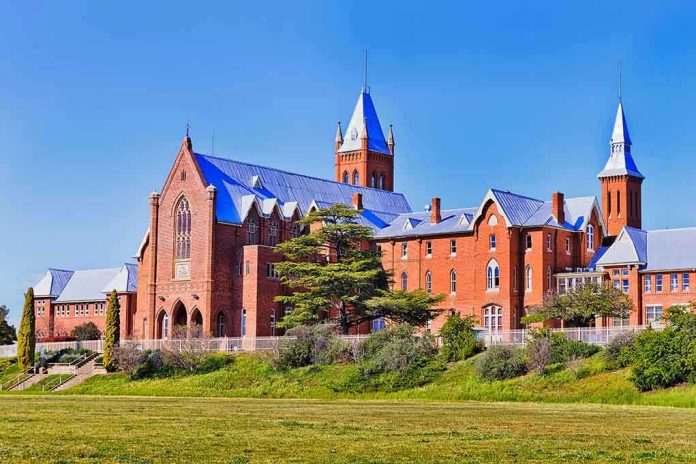 1844987860 Large red brick building with turrets and green lawn.