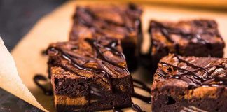 Chocolate brownies with drizzled chocolate on parchment paper.