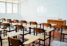 Empty classroom with desks, chairs, and whiteboard.