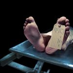 Feet of a deceased person on a coroners table with an identification tag