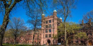 Historic university building surrounded by green grass and trees under a blue sky