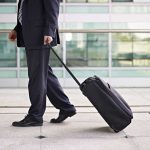 A businessman in a suit walking with a suitcase at an airport