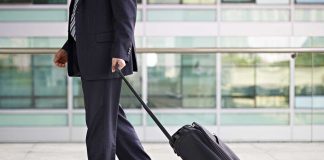 A businessman in a suit walking with a suitcase at an airport