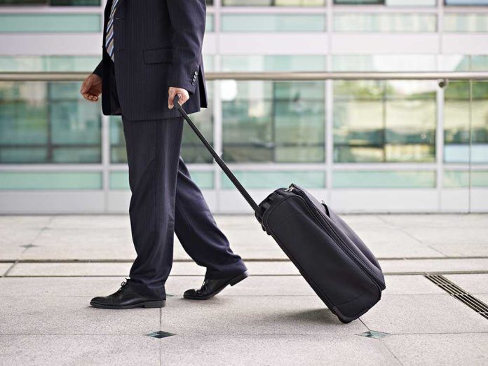 A businessman in a suit walking with a suitcase at an airport