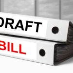 Two file folders labeled DRAFT and BILL stacked on a desk