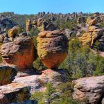 Unique rock formations surrounded by greenery under a clear blue sky
