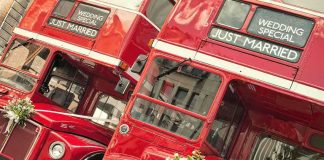 Two red double-decker buses decorated for a wedding with Just Married signs