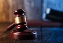 Gavel on wooden table in dimly lit room.