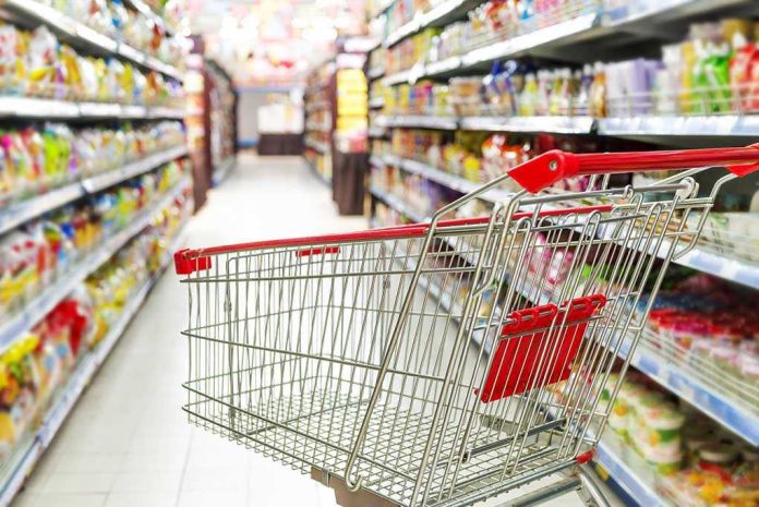 Empty shopping cart in grocery store aisle.