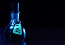 Dark bottle with skull-and-crossbones label on table.