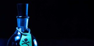 Dark bottle with skull-and-crossbones label on table.