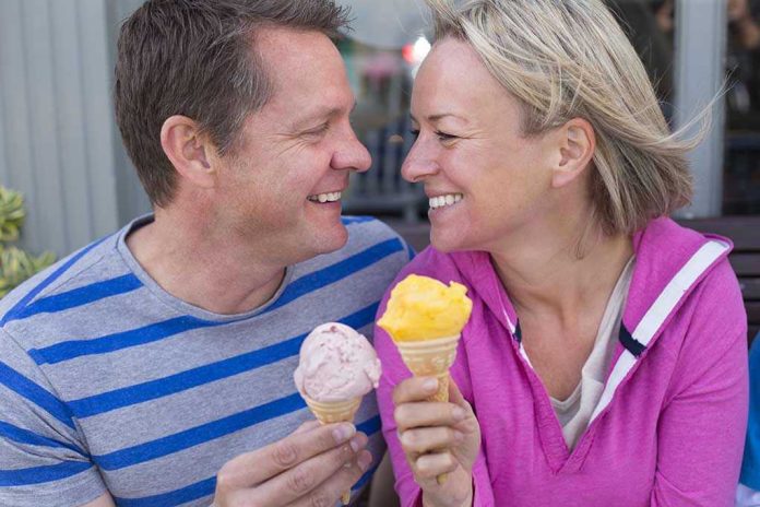 342652082 Couple smiling with ice cream cones outside bench