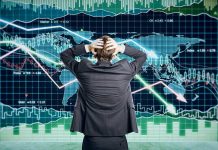 Person in front of falling stock market graph.