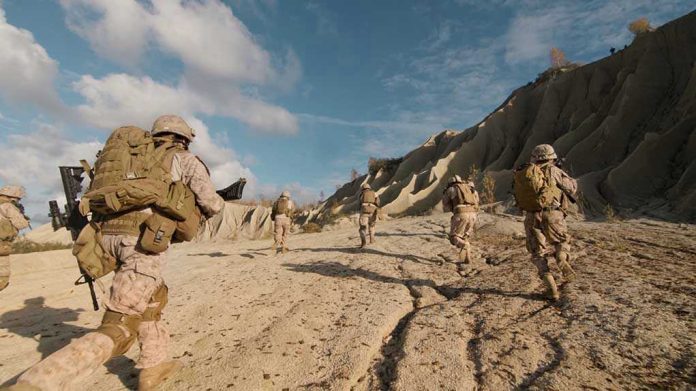 Soldiers running on rocky terrain with backpacks.