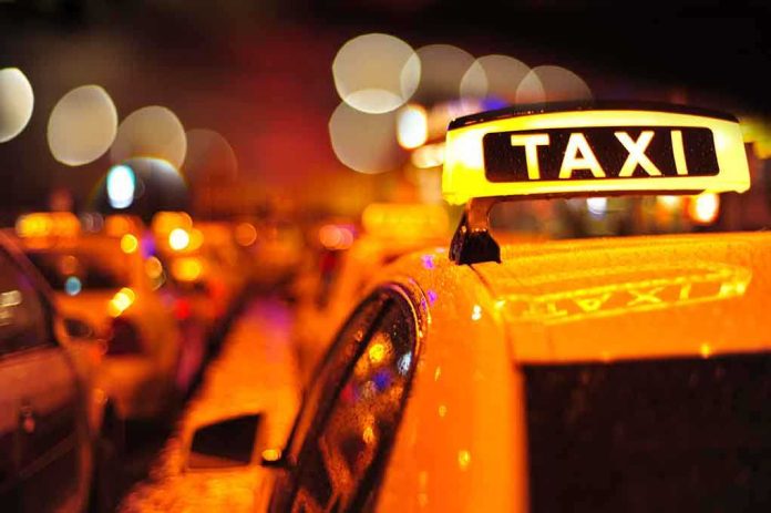 Close-up of a taxi sign illuminated at night with blurred city lights in the background