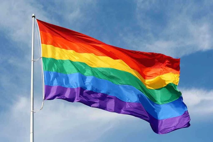 A rainbow flag waving against a blue sky