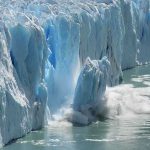 A glacier calving into the ocean, creating a splash of ice and water