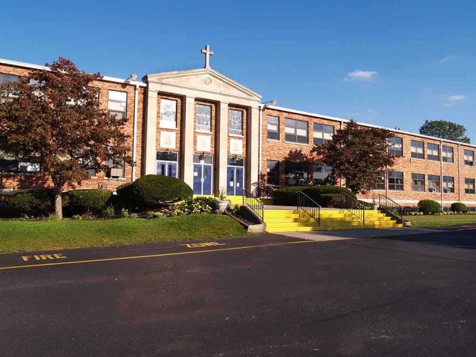 Exterior view of a brick school building with yellow steps and a cross on top