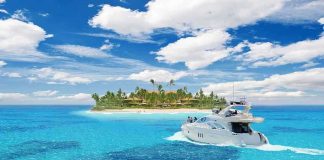 A luxury yacht cruising in clear blue waters near a tropical island