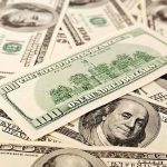 A collection of hundred dollar bills scattered on a surface