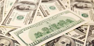 A collection of hundred dollar bills scattered on a surface