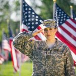 FBI Offers Reward For Air Force Specialist Wanted On Espionage Charges Soldier saluting in front of American flags outdoors.