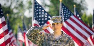 FBI Offers Reward For Air Force Specialist Wanted On Espionage Charges Soldier saluting in front of American flags outdoors.