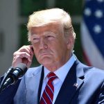 Trump’s Shocking Health Revelation: Fatal Diagnosis Man in a suit adjusting an earpiece.
