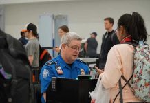 Mandatory Screenings Expand Across U.S Airports! TSA agent checks passengers documents at airport security.