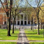 Swastika Flag Shocks NYU Graduation Students walking on a university campus with autumn trees and a historic building in the background