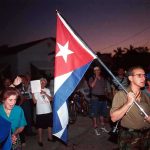 Cuban Dictator Faces U.S. Indictment: 30-Year Scandal A group of people participating in a protest march holding a Cuban flag