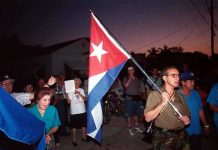Cuban Dictator Faces U.S. Indictment: 30-Year Scandal A group of people participating in a protest march holding a Cuban flag