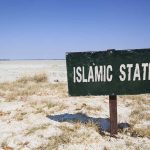 Dems Greenlight 400-Acre Islamic City Plans A weathered sign reading 'ISLAMIC STATE' in a barren landscape