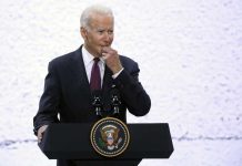 Biden Left Wondering During Dem Event A man in a suit speaking at a podium with a presidential seal
