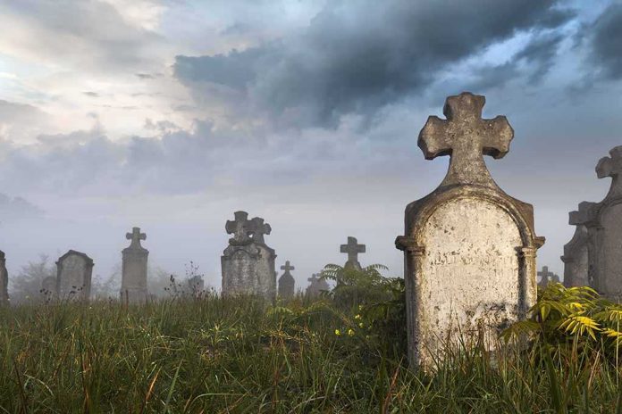 shutterstock_122534365 Foggy graveyard with tombstones and crosses under a cloudy sky