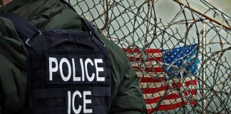 Hero ICE Agent Rescues Drowning Kid! Police officer in tactical gear standing near a barbed wire fence with an American flag in the background