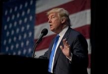 Trump’s Pastor Bro WITHDRAWS From Race! man in suit speaking at a podium with a US flag backdrop