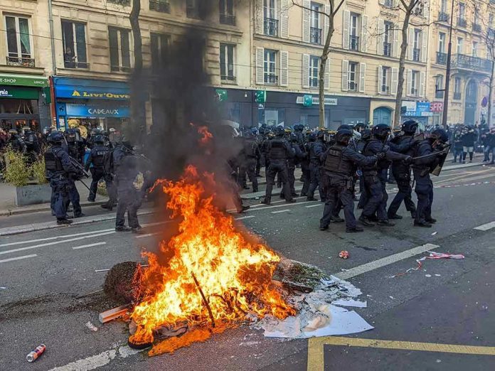 2261352259 Fire burning on the street amid police presence.