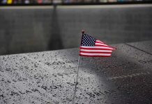 American flag on a rainy memorial nameplate.