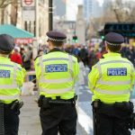 Terror Plot THWARTED: Boy, 14, Targets Mosques! Three police officers in high-visibility jackets stand facing a busy street