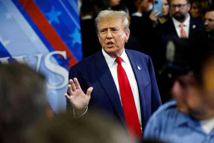 A man in a suit with a red tie speaking at a political event