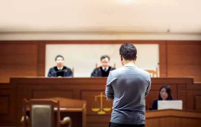 shutterstock_1049504825-1 defendant stands before judges in a courtroom