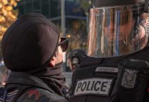 protester faces police officer in riot gear