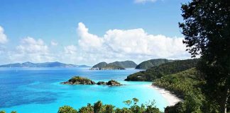 Americans Told To NOT Travel Here – Level 2 Warning! Scenic view of a tropical beach with clear blue water and lush greenery