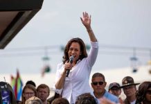 Kamala’s Endorsement SNUBBED – Candidate Says No! Woman speaking at outdoor event with raised hand.