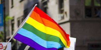 CREEP Dem Candidate Campaigned With 11 YEAR-OLD Child Drag Queen People holding and waving a rainbow flag.