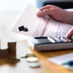 Americans Shut Out of Colleges – Migrants Granted Priority Hands calculating student loan with document and calculator