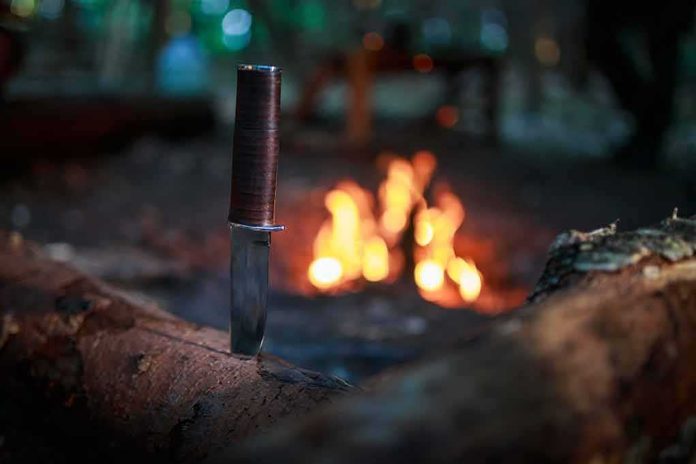 Hunting knife stuck in a log near a campfire